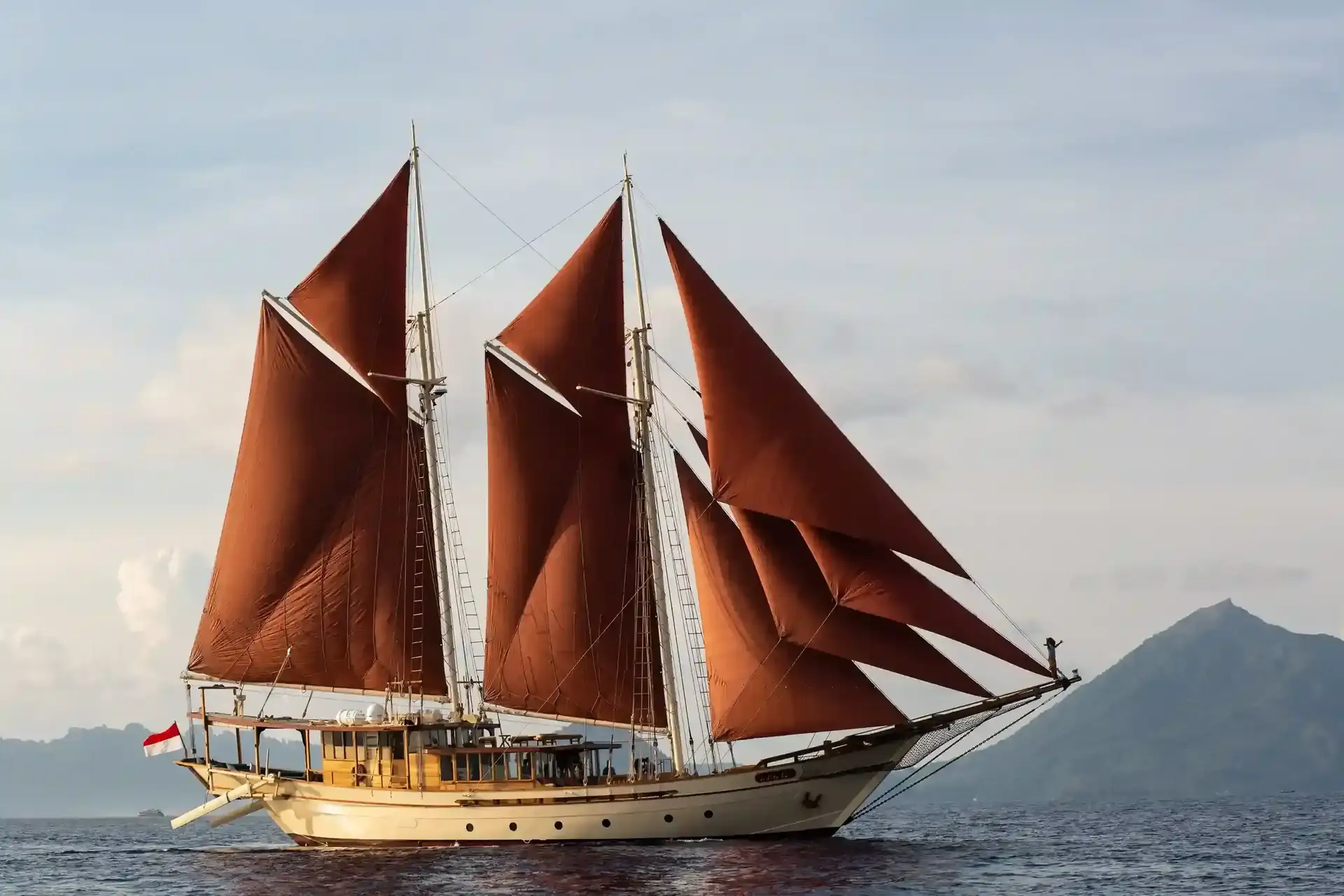 Phinisi schooner with red sails at sea